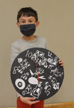 Zdjęcie, chłopiec prezentuje własnoręcznie przygotowany zegar