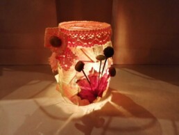 Zdjęcie, słoik przyozdobiony jesiennymi liśćmi ze świeczką w środku