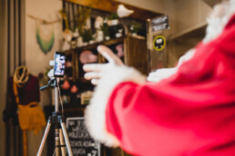 Zdjęcie, dłonie św. Mikołaja przed ekranem smartfona w trakcie rozmowy