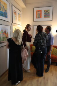 Na zdjęciu widac osoby, które oglądają wystawę kolorowych prac w galerii 
