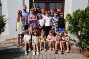 Grupka dzieci w kolorowych kwiecistych wiankach razem z instruktorem Krystianem Olszowskim 