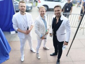 3 mężczyzn wokalistów ubranych w białe marynarki 