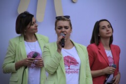 Zdjęcie, wokalistka w trakcie występu; w tle zespół