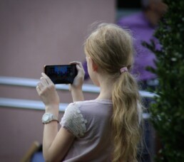Zdjęcie, dziewczynka robiąca zdjęcie smartfonem, widok z tyłu