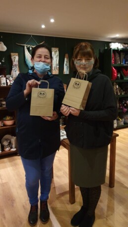Zdjęcie, dwie kobiety w sklepie z rękodziełem pokazują papierowe torebki