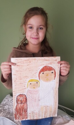 Zdjęcie, dziewczynka trzymająca w rękach swój rysunek