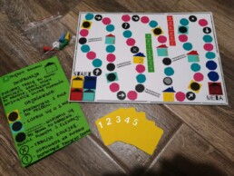 Zdjęcie; planszówka wykonana przez jednego z uczestników zajęć, kadr wypełnia plansza, zasady gry i 5 żółtych kart